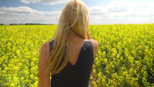 젊은 금발 여 자가 아름 다운 유채 밭에서 포즈 — 비디오