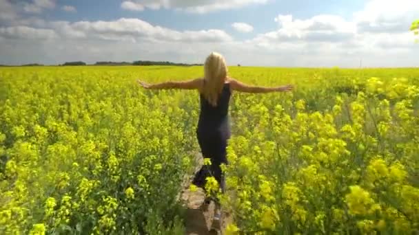 Joven rubia posando en hermoso campo de colza — Vídeo de stock