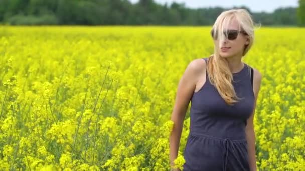 Ung blond kvinna poserar i vackra raps fält — Stockvideo