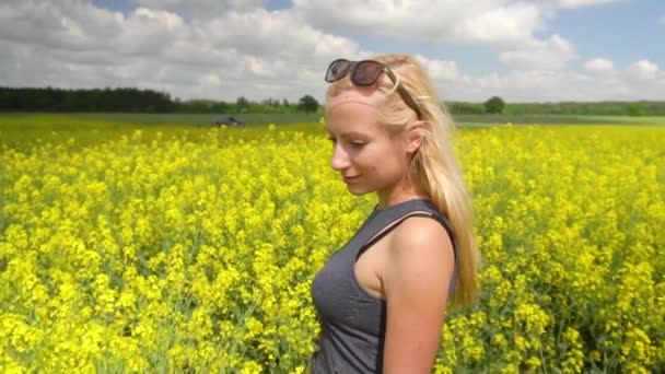 Jonge blonde vrouw poseren in mooie koolzaad veld — Stockvideo