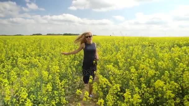 Молода блондинка позує в красивому полі ріпаку — стокове відео
