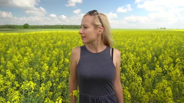 Joven rubia posando en hermoso campo de colza — Vídeos de Stock