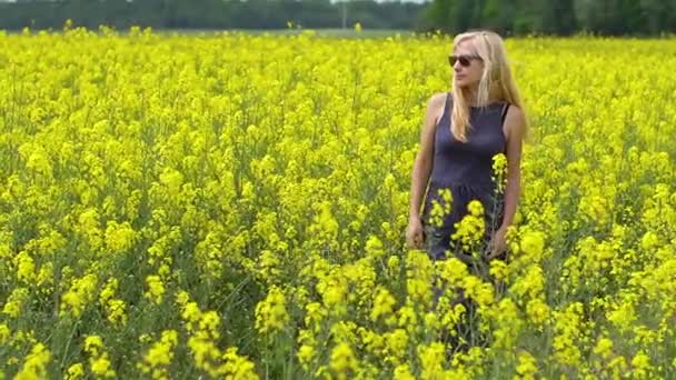 Giovane donna bionda in posa in un bellissimo campo di colza — Video Stock