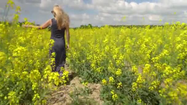 Mladá blondýnka pózuje v krásném řepkové pole — Stock video