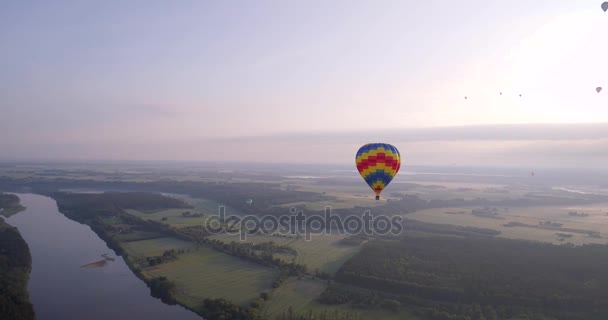 Воздушный шар над зелеными землями рано утром — стоковое видео