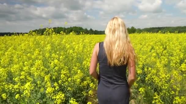 Joven rubia posando en hermoso campo de colza — Vídeos de Stock