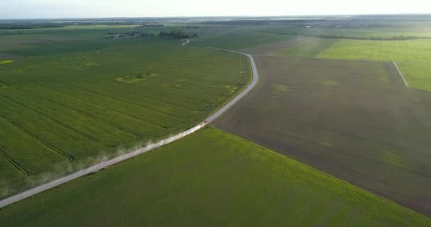 Havada, yeşil tarlalarda yolda hareket traktörün havadan görünümü — Stok video