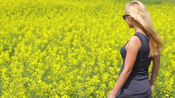 Giovane donna bionda in posa in un bellissimo campo di colza — Video Stock