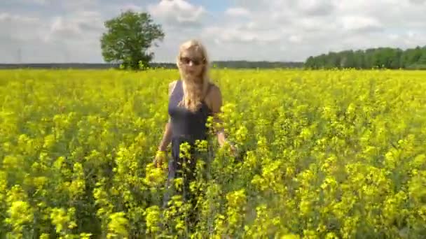 Joven rubia posando en hermoso campo de colza — Vídeos de Stock