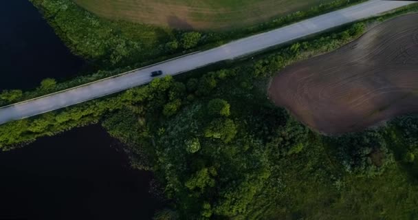 Luftaufnahme eines Geländewagens, der sich auf der Straße in grünen Feldern bewegt — Stockvideo