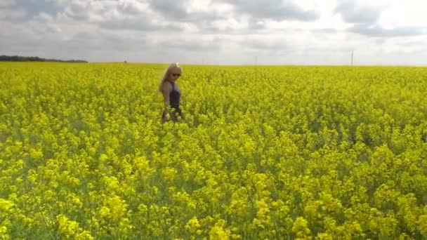 Jonge blonde vrouw poseren in mooie koolzaad veld — Stockvideo