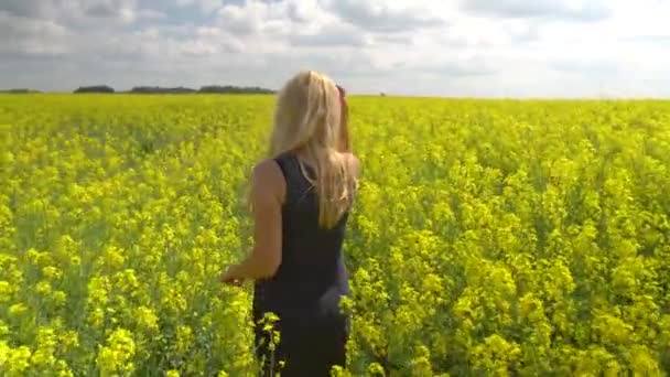 Jovem mulher loira posando em belo campo de colza — Vídeo de Stock