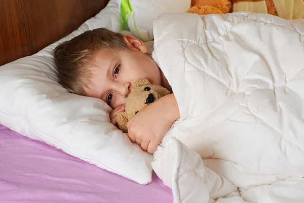 Мальчик с плюшевым мишкой в постели — стоковое фото