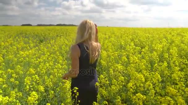 Young blonde woman posing in beautiful rapeseed field — Stock Video