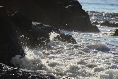 Dalgalar ve taşlı sahil güneş ışığı altında görünümü 