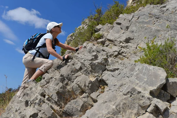 woman climbs mountain side