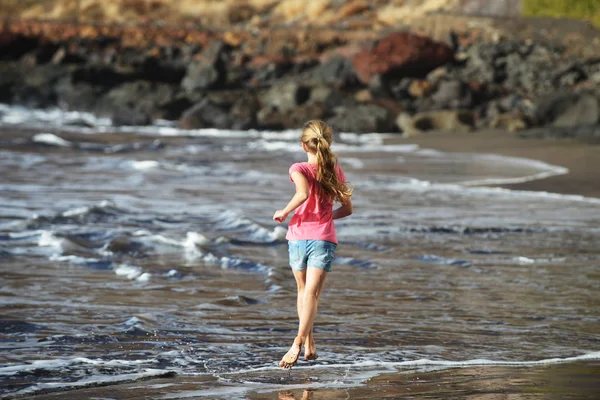 Meisje speelt aan zandstrand — Stockfoto