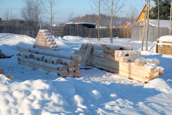 Smooth logs prepared for construction lying on snow — Stock Photo, Image
