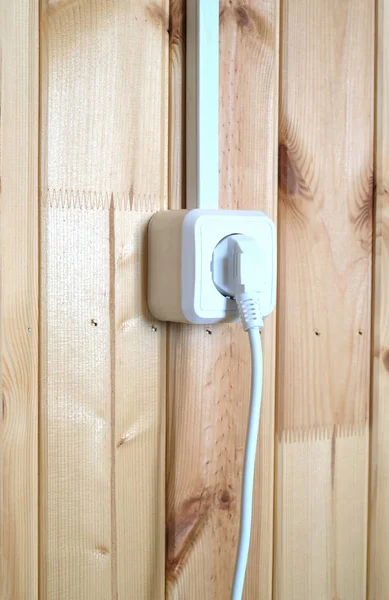 Białe wtyczki elektrycznej w gniazdo na ścianie drewnianej deski pionowe — Zdjęcie stockowe