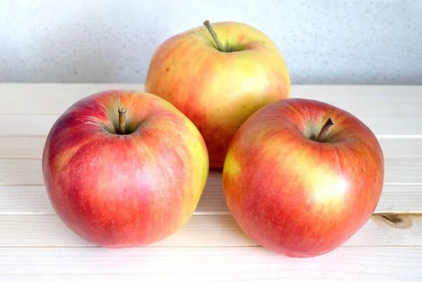 Drei große reife Äpfel im Holzregal — Stockfoto