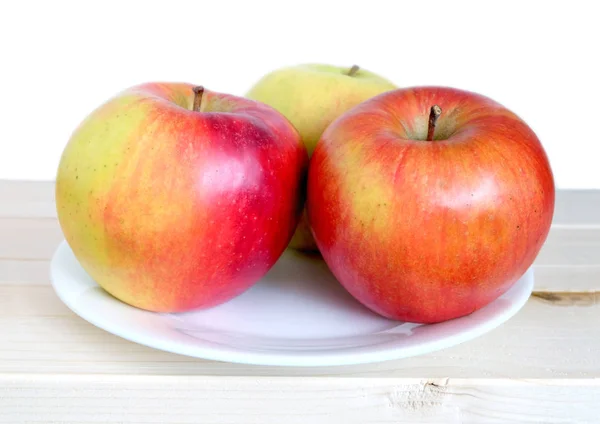 Three big ripe apples on white plate closeup