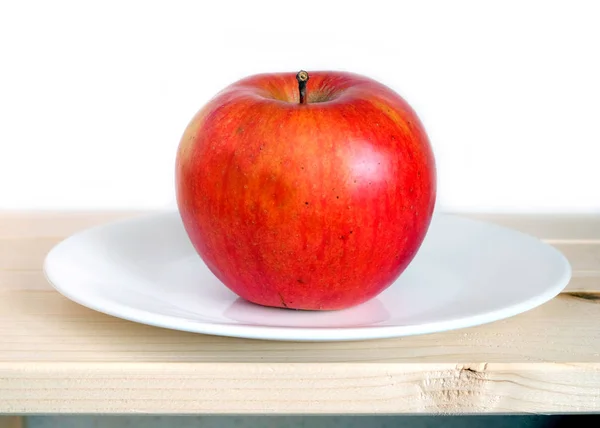 Big ripe apple on white plate closeup — Stock Photo, Image