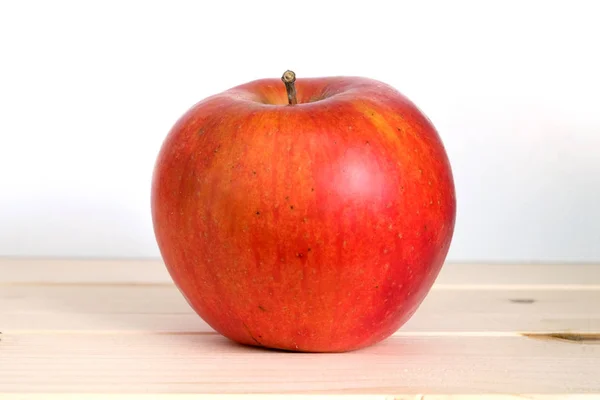 Big ripe red apple in beige wooden shelf closeup — Stock Photo, Image