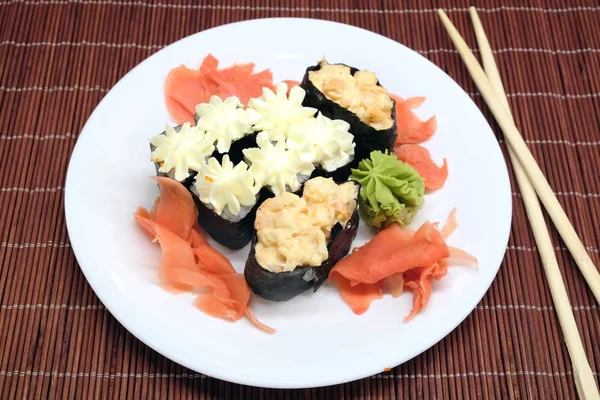 Sushi na bílé plotně s hůlkami nad proutěný slaměné mat closeup — Stock fotografie