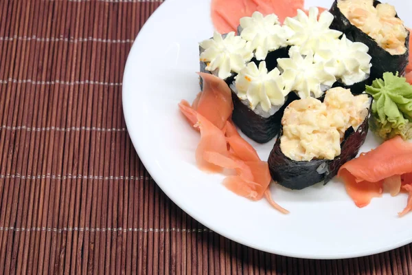 Sushi auf weißem Teller über Weidenstrohmatte Nahaufnahme — Stockfoto