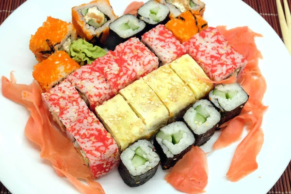 Sushi auf weißem Teller mit Essstäbchen über Weidenmatte Nahaufnahme — Stockfoto