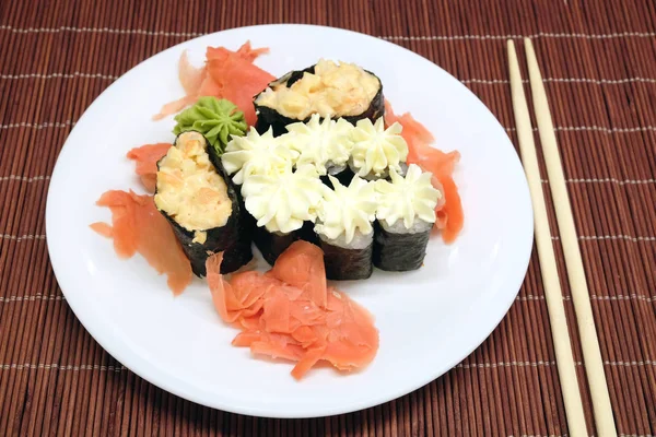 Sushi su piatto bianco con bacchette sopra paglia di vimini primo piano — Foto Stock