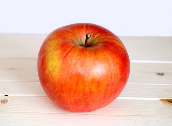 Big ripe red apple in beige wooden shelf closeup — Stock Photo, Image