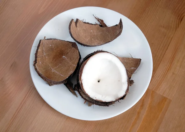 Zerkleinerte Kokosnussschale und Kokosfrüchte auf weißem Teller Nahaufnahme — Stockfoto