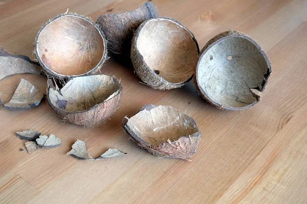 Stillleben mit gebrochenen Kokosnussschalen-Fragmenten auf braunem Holztisch — Stockfoto