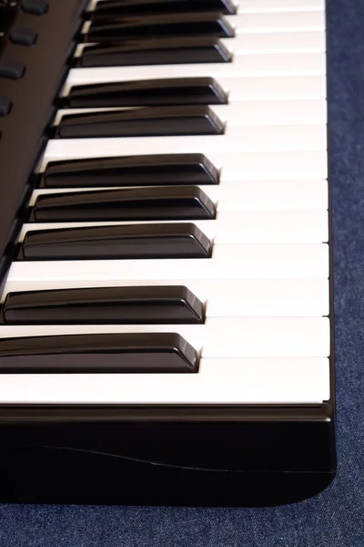 Клавиатура фортепиано с белыми и черными клавишами на голубом хлопковом фоне — стоковое фото