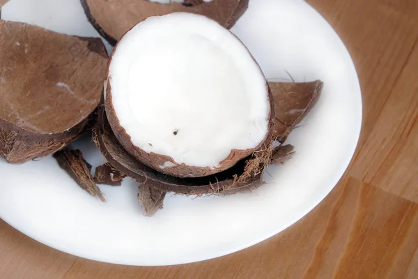 Casca de coco esmagada e fruta de coco em close-up placa branca — Fotografia de Stock