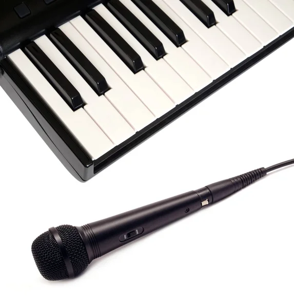 Top view of piano keyboard and black vocal microphone on white background closeup — Stock Photo, Image