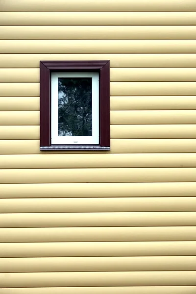 Parede de edifício com janela de plástico coberta com painéis de tapume bege vista frontal — Fotografia de Stock