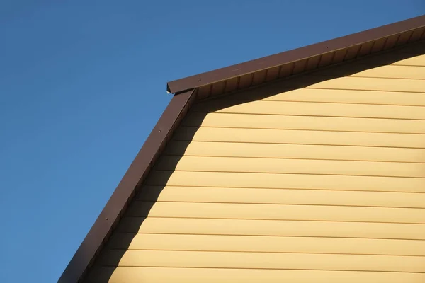 노란 창틀과 갈색 금속 지붕 전면 보기 농촌 집 벽의 일부 — 스톡 사진