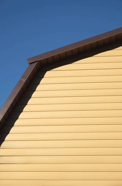 Parte da casa rural Parede coberta com tapume amarelo e telhado de metal marrom vista frontal — Fotografia de Stock