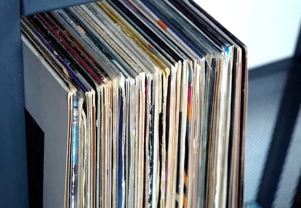 Stack of many vinyl records in old color covers on a shelf side view