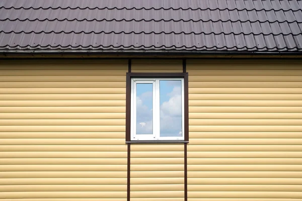 Будівництво металевого даху і стіни оброблені бежевими панелями з білим пластиковим вікном — стокове фото