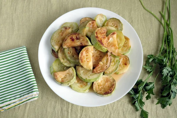Fatias de abobrinha fritas na placa branca com verdes — Fotografia de Stock
