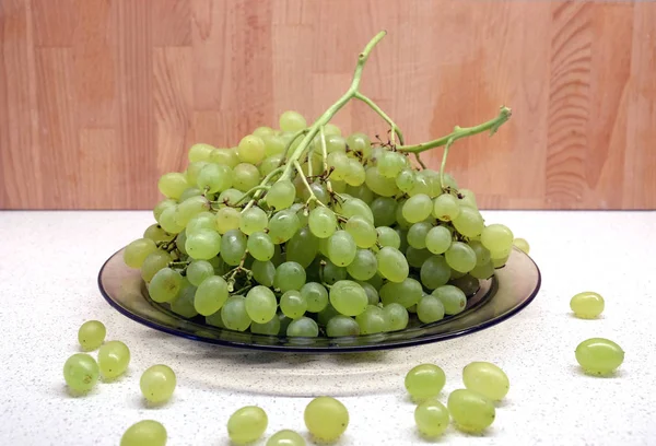 Bunches de uva verde madura em placa transparente na mesa da cozinha vista frontal closeup — Fotografia de Stock