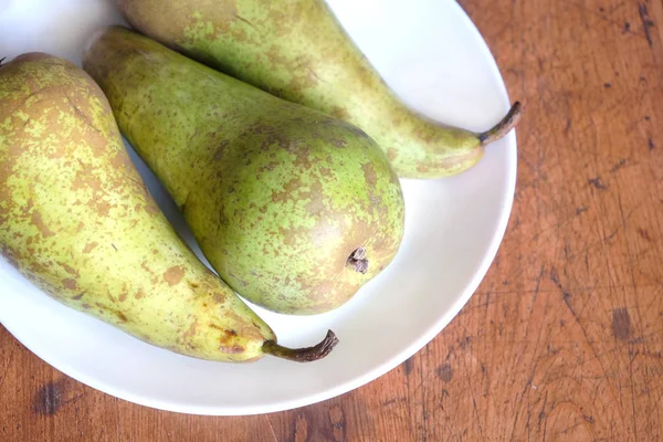 Drie lange ripe groene peren op witte bleke boven bekijken closeup — Stockfoto