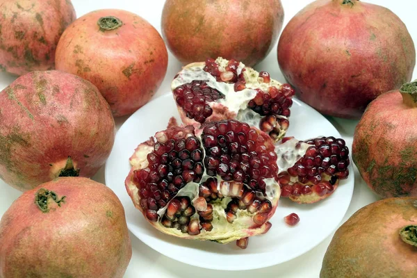 Hele Halve Granaatappels Met Rijpe Zaden Plaat Geïsoleerd Een Witte — Stockfoto