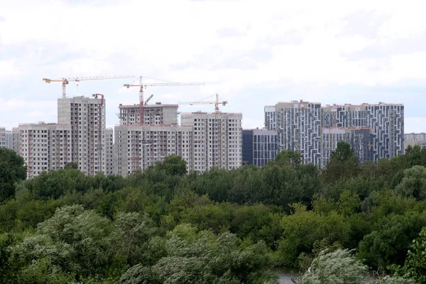 City construction. Landscape with cranes and new block of flats construction in new green ecological district sky with white clouds in summer day