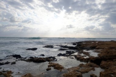 Yaz gününde deniz kıyısında taşlar ve gökyüzünde bulutlar ile güzel günbatımı ile Manzara