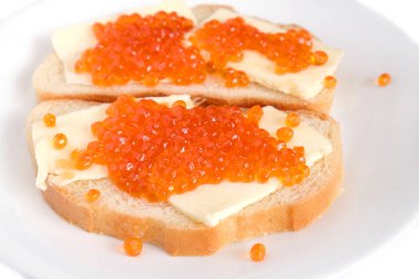 Tereyağı ve üzerinde beyaz ekmek yalan yuvarlak tabakta beyaz arka plan yan görünüm üzerinde izole kırmızı somon havyar ile iki sandviç