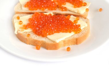 Tereyağı ve üzerinde beyaz ekmek yalan yuvarlak tabakta beyaz arka plan yan görünüm üzerinde izole kırmızı somon havyar ile iki sandviç